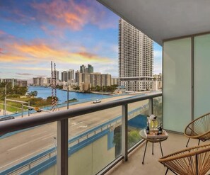 A balcony with a view of a cityscape, including high-rise buildings and a body of water.
