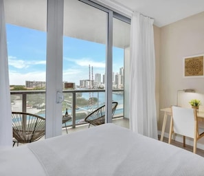 Habitación de hotel con cama, escritorio, silla y vista a la ciudad y al agua.