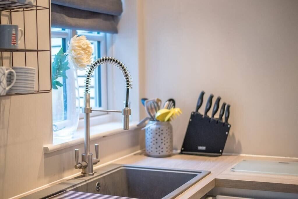 A kitchen with a modern faucet, a knife block, and a window with a plant.