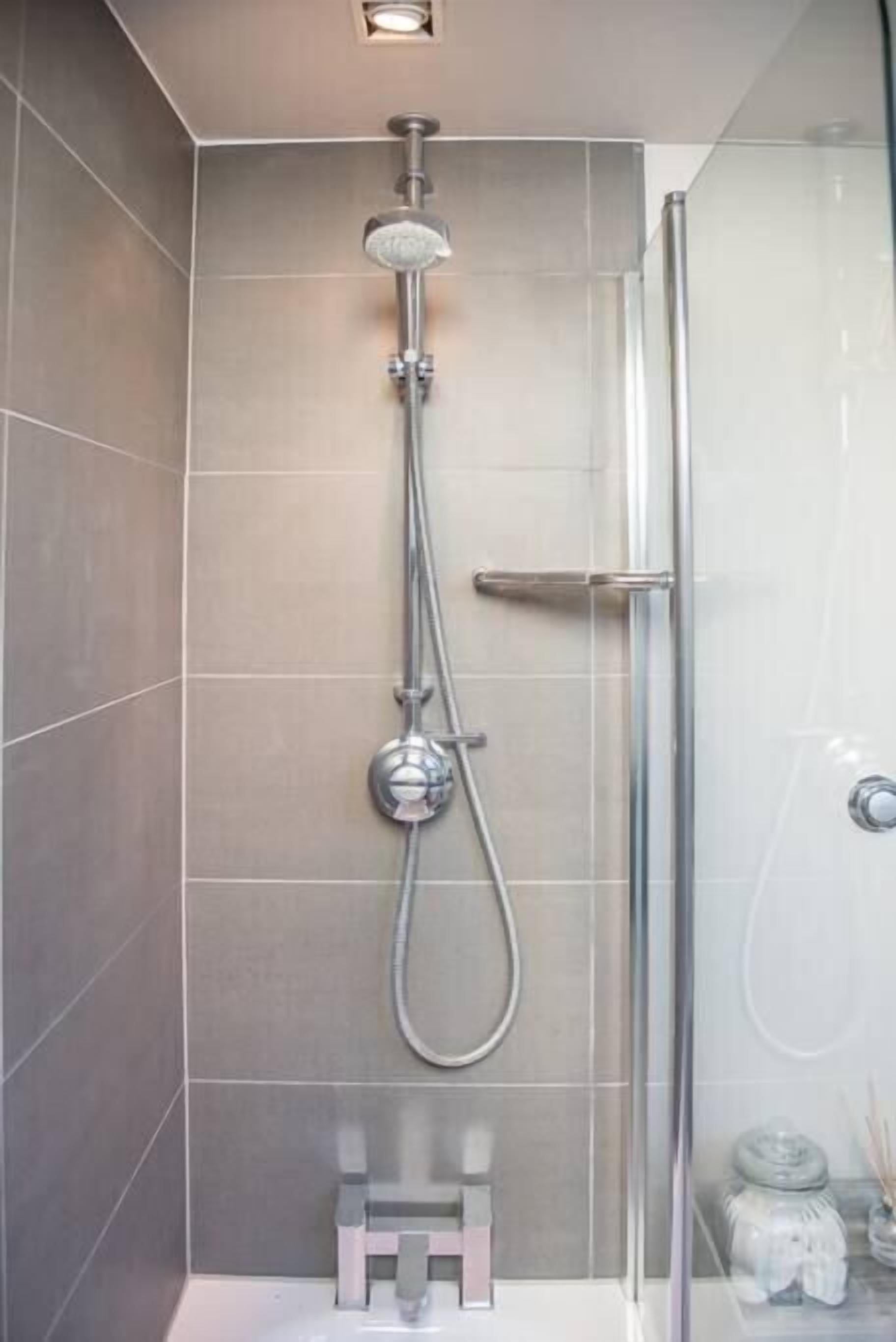 A modern shower with a glass enclosure, a handheld showerhead, and a wall-mounted faucet.