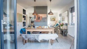 A dining area with a wooden table, two hanging pendant lights, and a bench with a fur throw.