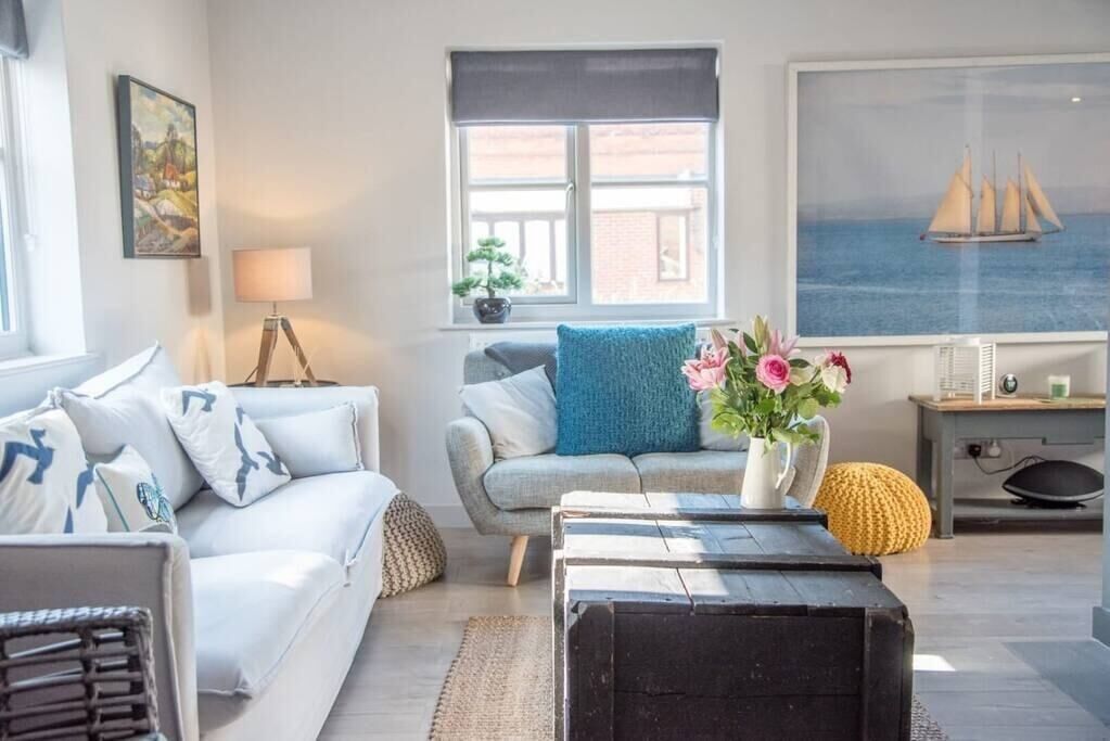 Ein modernes Wohnzimmer mit einer Couch, einem Couchtisch und einem Fenster mit Meerblick.