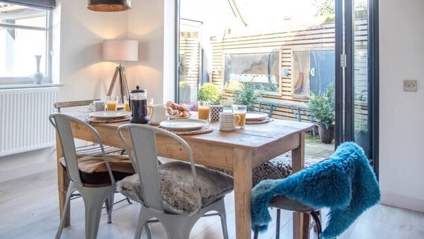 A dining area with a wooden table, metal chairs, and a blue throw blanket.