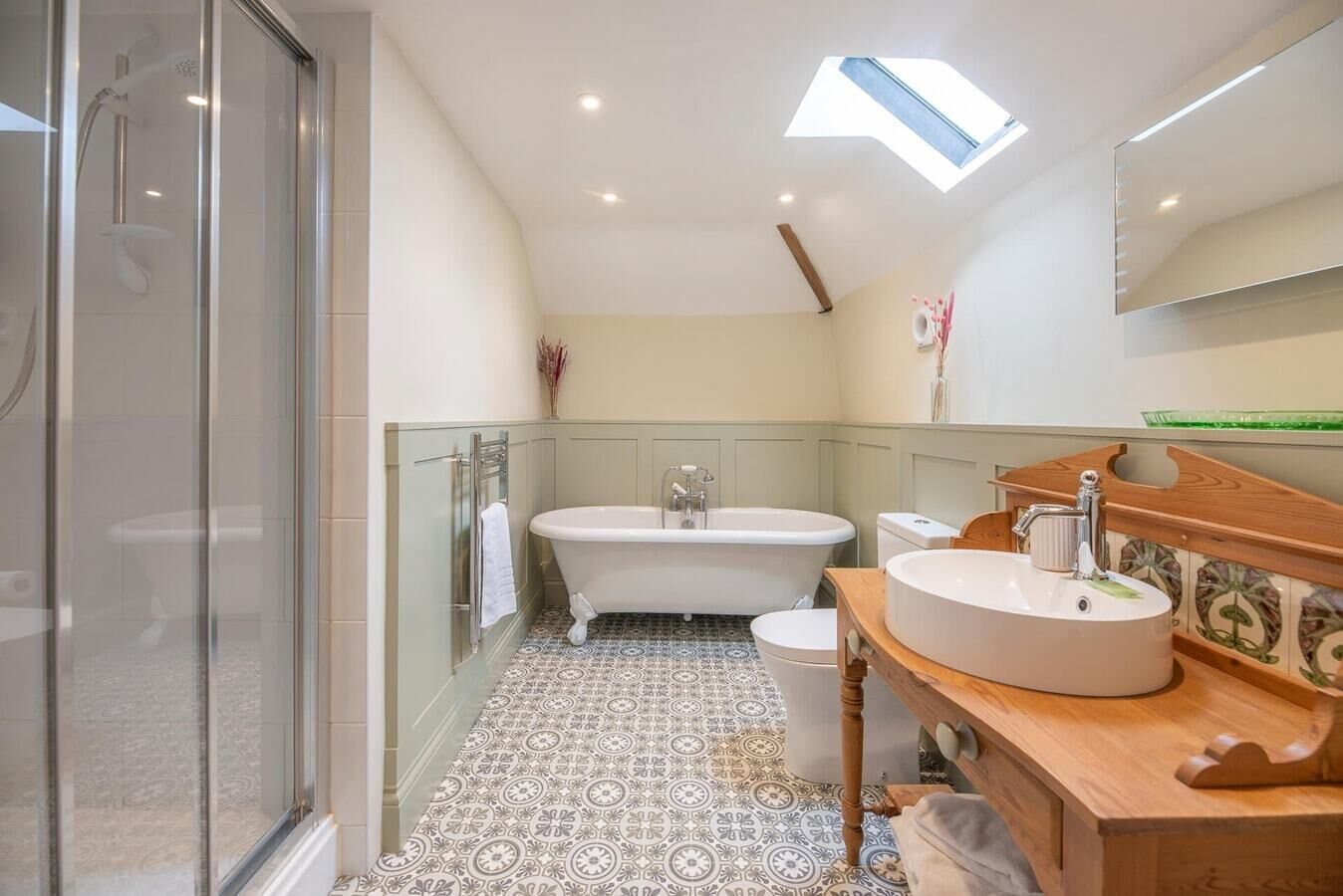 A bathroom with a freestanding bathtub, a toilet, and a sink with a wooden vanity.