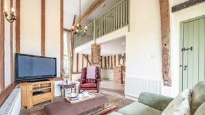Een ruime woonkamer met een grote flatscreen televisie, een leren fauteuil, een bank en een houten tv-meubel.