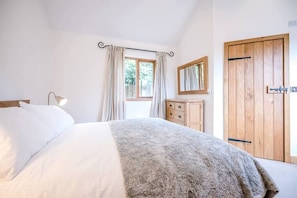 Une chambre à coucher avec un lit, une commode, un miroir et une porte en bois.
