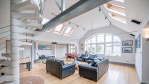 A spacious living area with a spiral staircase, a pool table, and a large window providing natural light. - The Links, Southwold (Southwold)