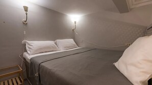A single bed with white bedding in a room with two wall-mounted light fixtures.