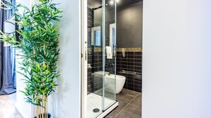A modern bathroom with a glass-enclosed shower, a toilet, and a potted bamboo plant. - Boutique Flaminio   150 m from Piazza del Popolo (ROMA)