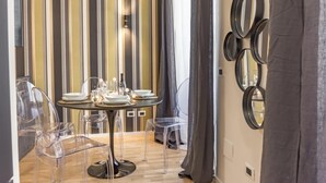 A dining area with a round table set for four, clear chairs, striped wallpaper, and a wall with circular mirrors. - Boutique Flaminio   150 m from Piazza del Popolo (ROMA)