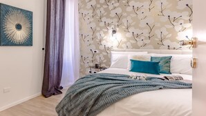 A bedroom with a bed, a large abstract painting, a patterned wallpaper, and a window with curtains. - Boutique Flaminio   150 m from Piazza del Popolo (ROMA)