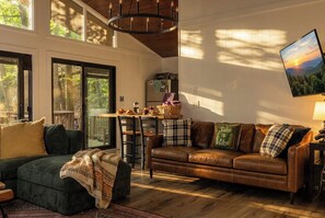 A cozy living room with a leather sofa, a green couch, and a dining area with a table and chairs.