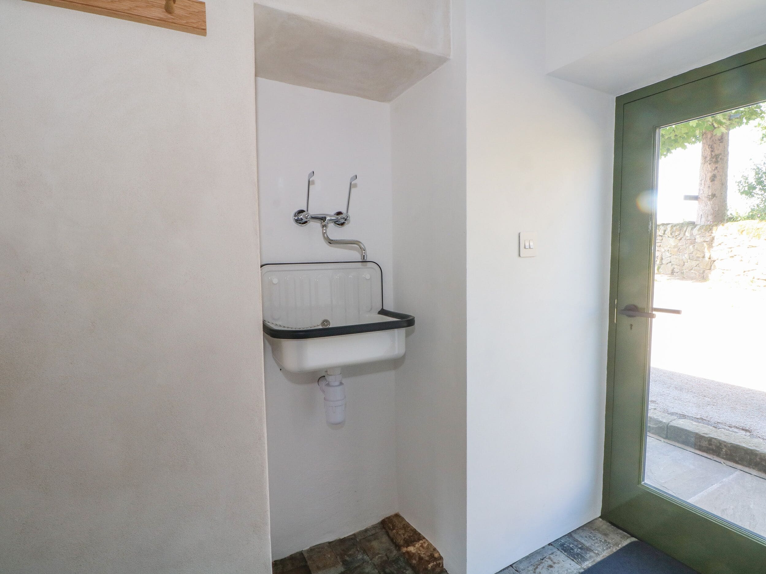 A small bathroom with a white sink, a radiator, and a green door.