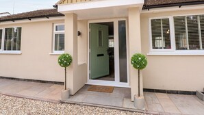 A two-story house with a front porch, a green door, and two potted plants. - Daisy Tree Cottage (Woodhall Spa)