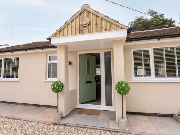 A two-story house with a front porch, a green door, and two potted plants. - Daisy Tree Cottage (Woodhall Spa)