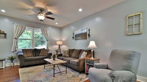 A living room with a ceiling fan, two couches, a coffee table, and a rug.