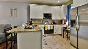 A compact kitchen with white cabinets, a stainless steel refrigerator, and a microwave.