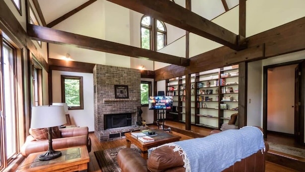 A spacious living room with a fireplace, leather sofas, a coffee table, and a bookshelf.