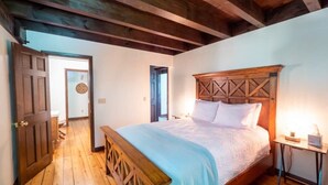A bedroom with a wooden bed, a bench, and a bedside table with a lamp.