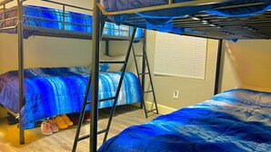 A bunk bed room with blue bedding and a ladder. - STOP INN STAY HOSTELS (Houston)