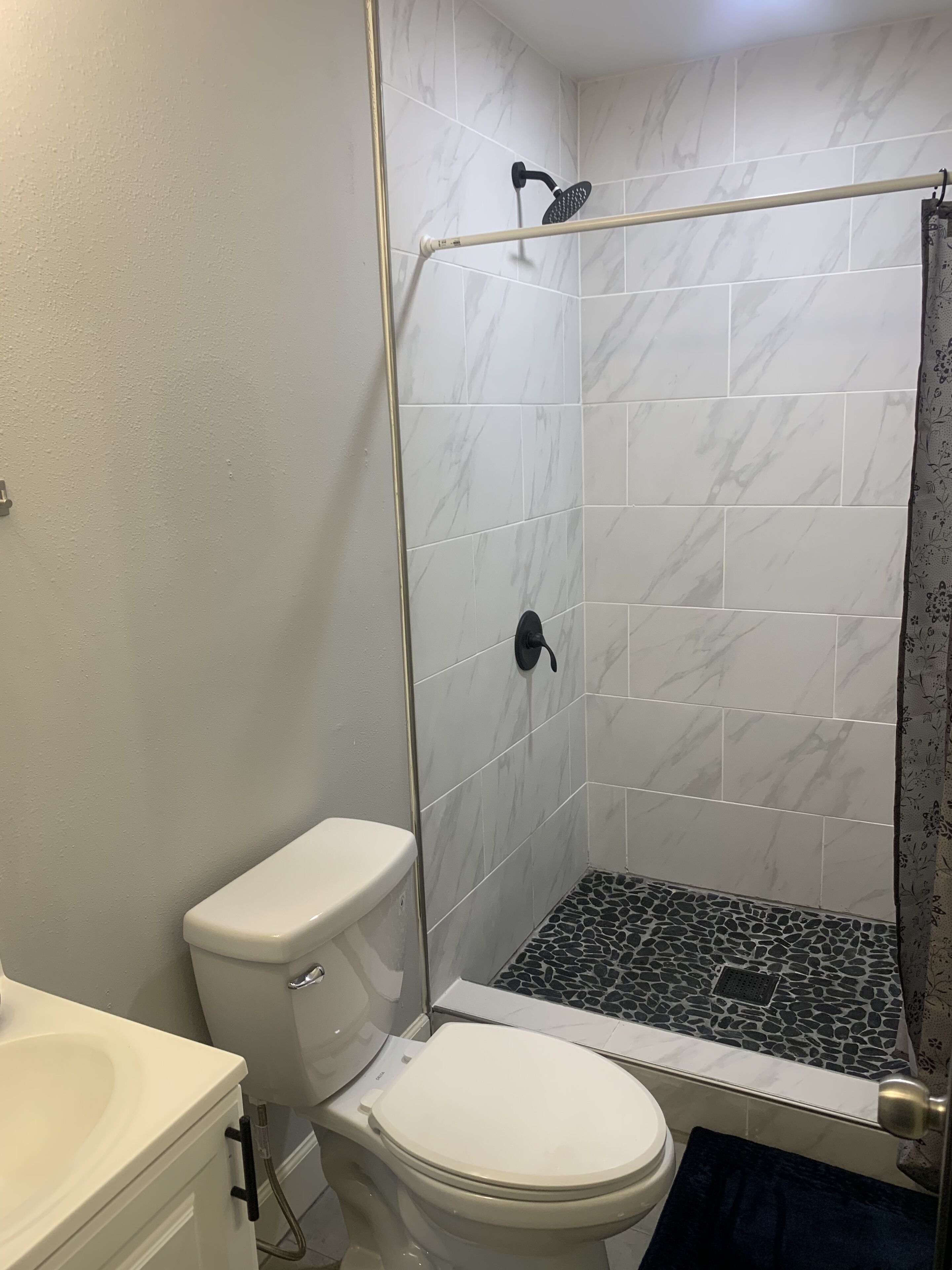 A bathroom with a shower, toilet, and sink.