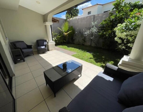 A patio area with a sofa, two chairs, and a small table.