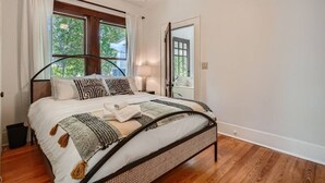 A bedroom with a bed, a window, a door, and a nightstand. - Spacious 2/2 Home Prime Location Mins to DT/SOCO & SXSW Top Spots (Austin)
