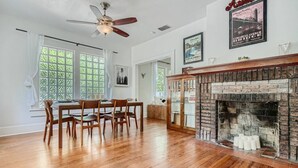 A dining area with wooden chairs and a table, a brick fireplace, and a ceiling fan. - Spacious 2/2 Home Prime Location Mins to DT/SOCO & SXSW Top Spots (Austin)