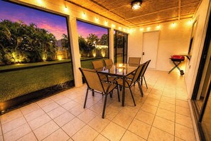 An outdoor patio with a glass table and chairs, a barbecue grill, and a view of palm trees. - Centrally located 4/2 Home with a private backyard available for Longer Stays! (Port St. Lucie)
