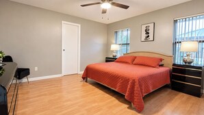 A bedroom with a bed, bedside tables, a desk, and a chair. - Centrally located 4/2 Home with a private backyard available for Longer Stays! (Port St. Lucie)