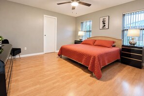 A bedroom with a bed, bedside tables, a desk, and a chair. - Centrally located 4/2 Home with a private backyard available for Longer Stays! (Port St. Lucie)