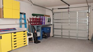 Ett garage med en gul arbetsbänk, en vit stol och en stängd garagedörr.