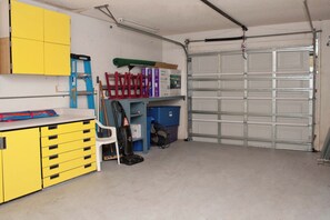 Eine Garage mit einem gelben Werkstisch, einem weißen Stuhl und einer geschlossenen Garagentür.