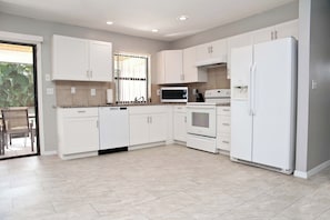 Eine moderne Küche mit wei ßen Schränken, einer Mikrowelle, einem Backofen und einem Kühlschrank.