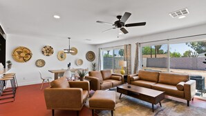 A spacious living room with a large sofa, a coffee table, and a dining area with chairs and a table. - Newer, Modern, Work Friendly 2 Bedroom Condo near Downtown PHX (Phoenix)