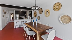 A modern kitchen with dark cabinets, a stainless steel refrigerator, and a central island with stools. - Newer, Modern, Work Friendly 2 Bedroom Condo near Downtown PHX (Phoenix)
