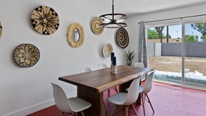 A dining area with a wooden table, white chairs, and decorative wall plates. - Newer, Modern, Work Friendly 2 Bedroom Condo near Downtown PHX (Phoenix)