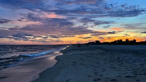 A beach with footprints leading to the water, a clear sky, and a distant horizon. - ISLAND CLUB- East End OCEANFRONT Ground Level unit with gazebo and OCEAN VIEW (St. George Island)