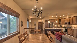 A spacious kitchen with wooden cabinets, a dining area with a large wooden table and chairs, and a cozy seating area with a sofa. - Walkable Bigfork Townhome: Fish, Hike & Ski! (Bigfork)