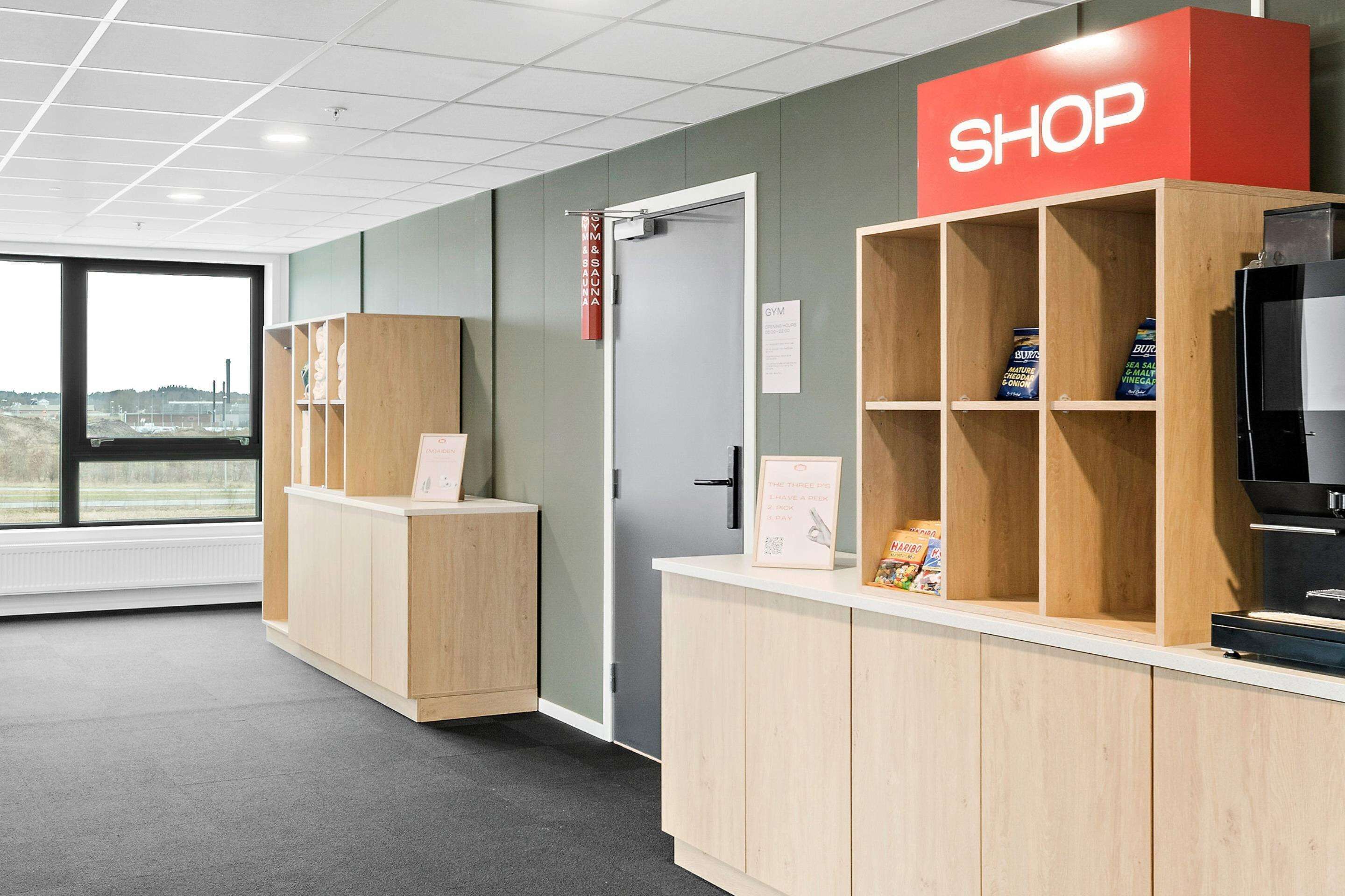 Ein Empfangsbereich mit einem 'SHOP'-Schild, Holzauslagen und einer Theke mit Produkten.