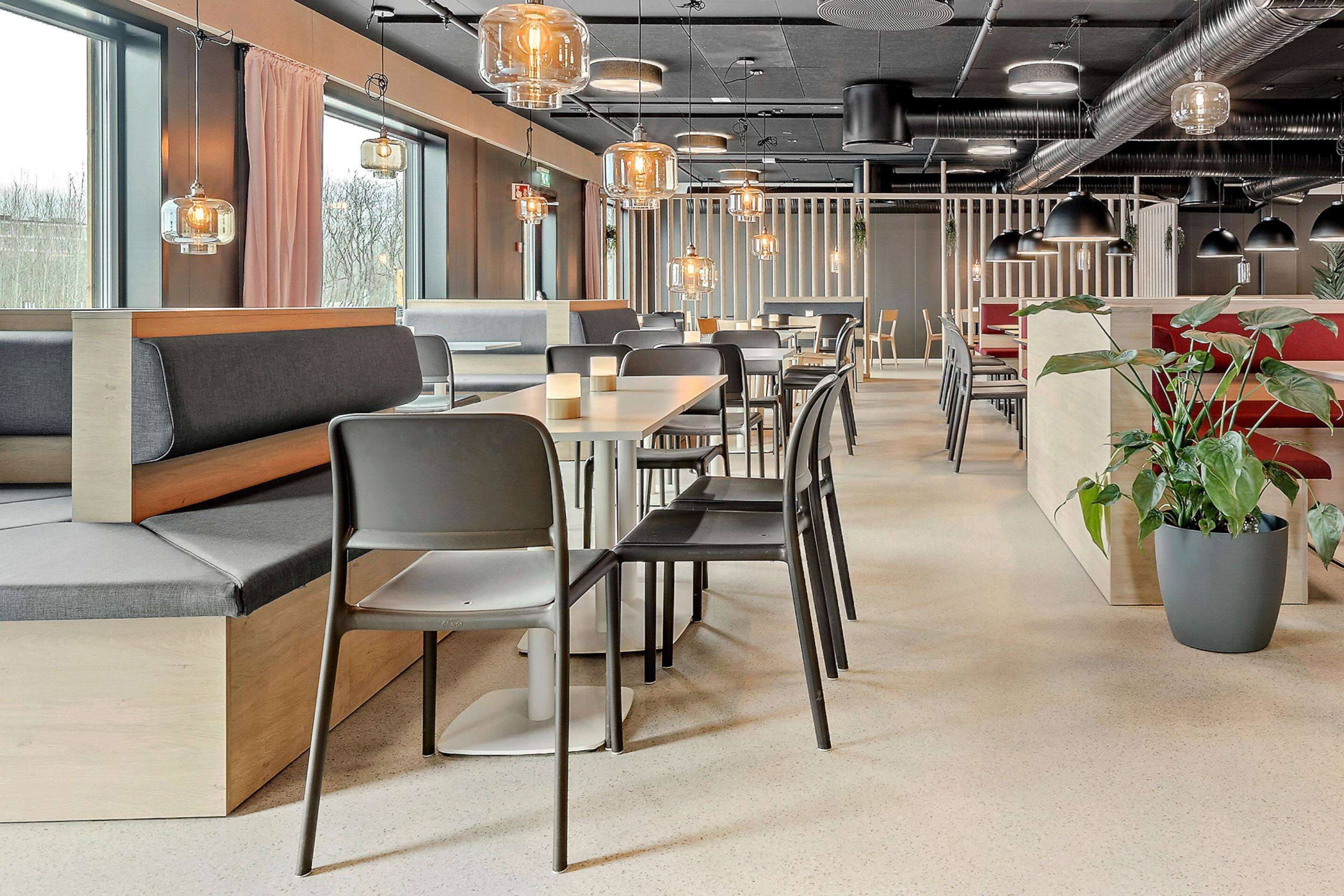 A modern restaurant with booths, tables, and hanging pendant lights.
