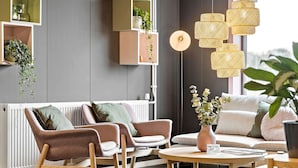 Una sala de estar moderna con sofá, sillones, una mesa de centro y lámparas colgantes de ratán.