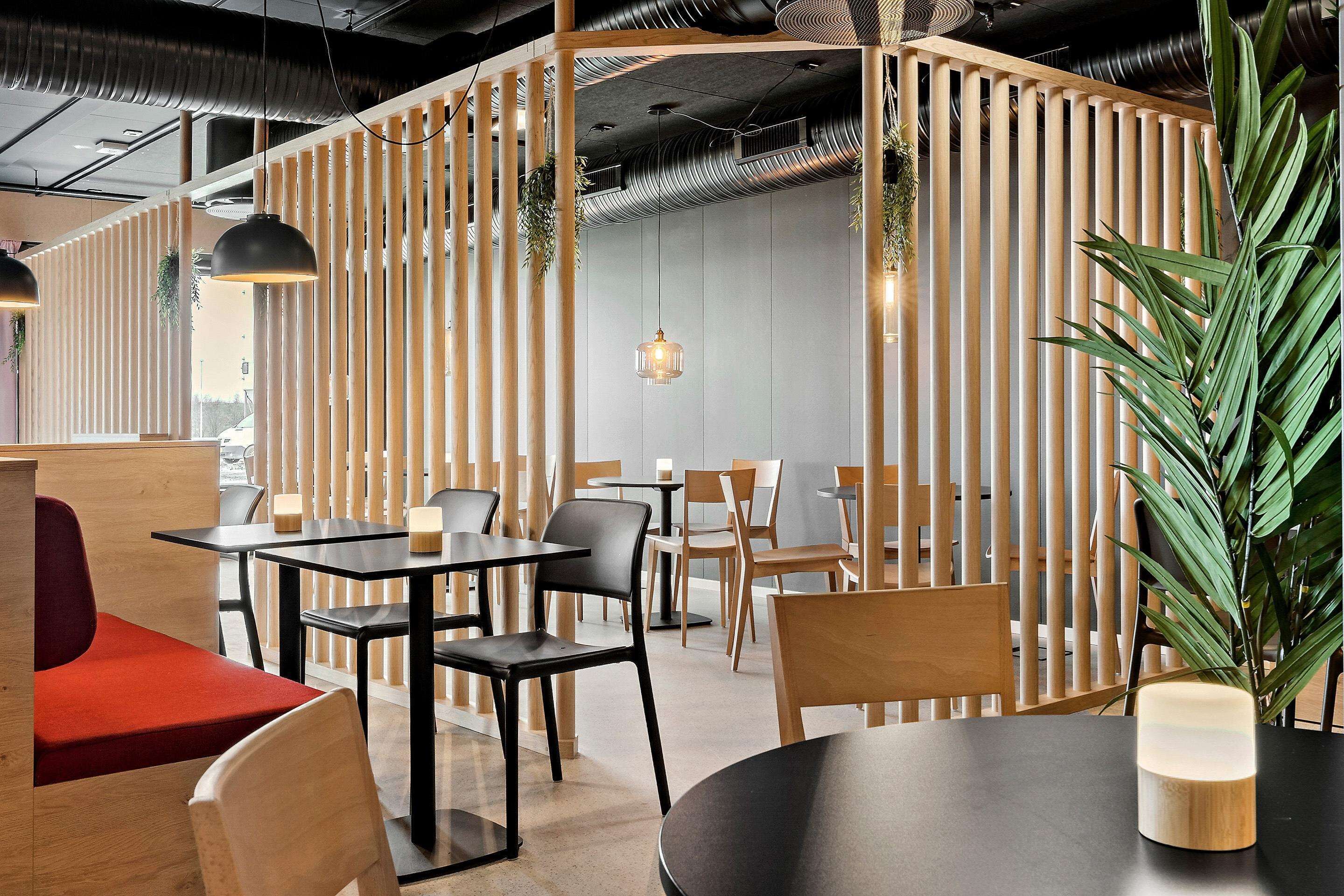 A modern restaurant with wooden partitions, black and wooden tables, and chairs.