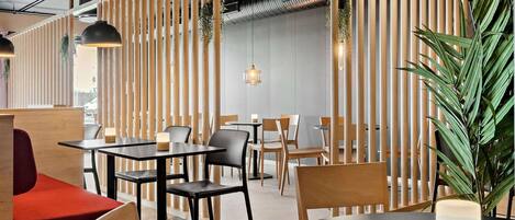 A modern restaurant with wooden partitions, black and wooden tables, and chairs.