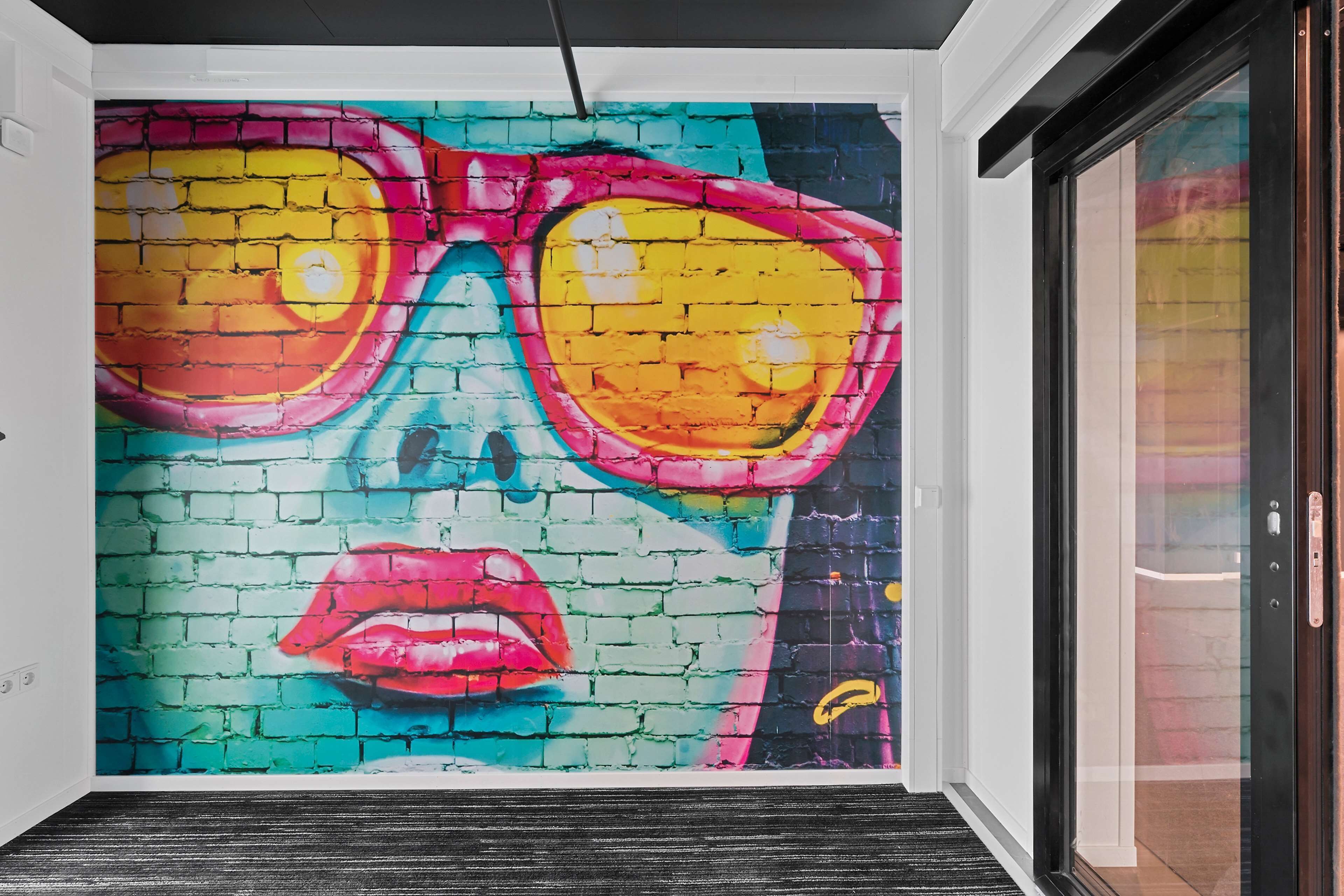 A vibrant mural of a face with sunglasses on a brick wall.