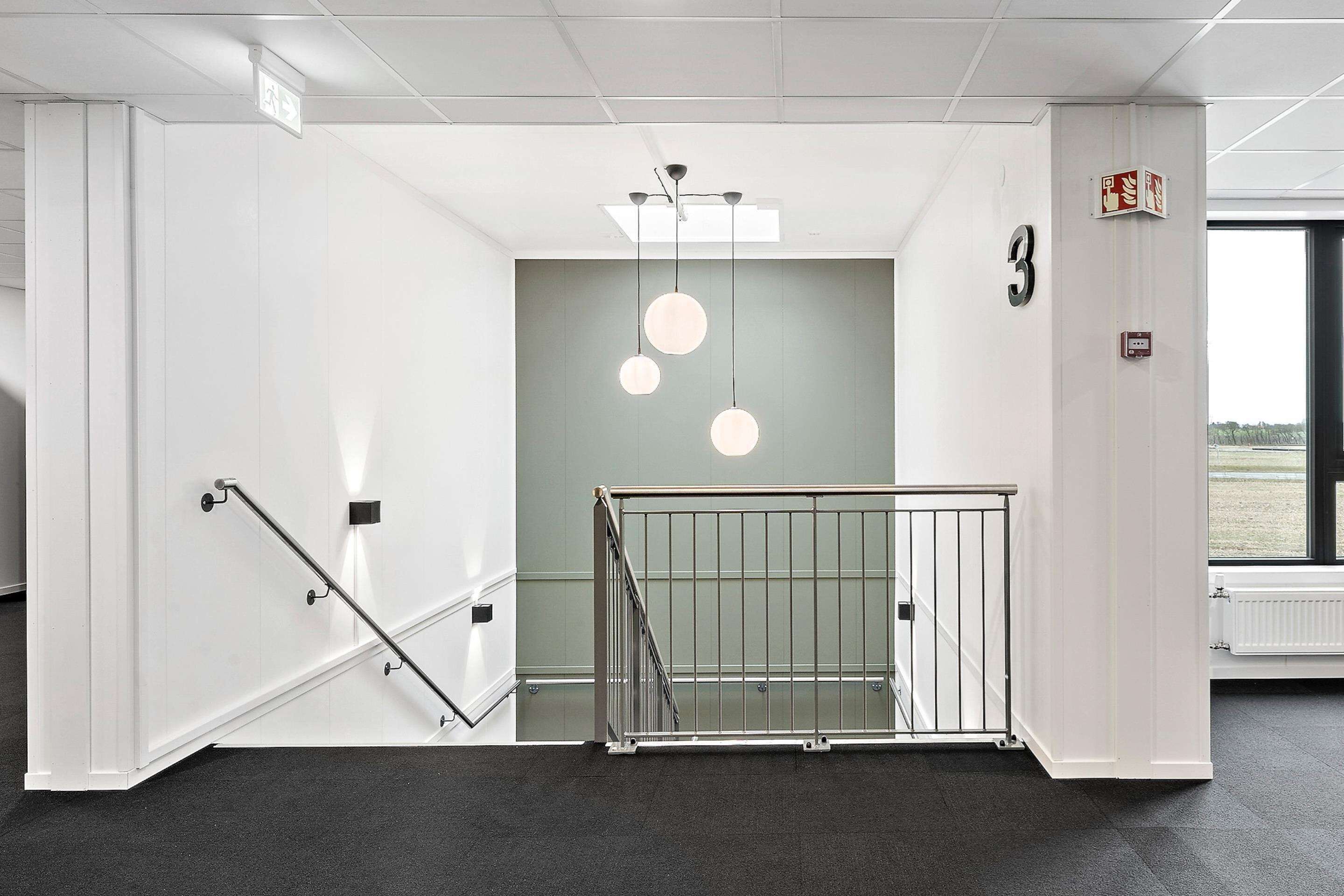 Et moderne interiør med trappe, loftlampe og et vindue med udsigt.