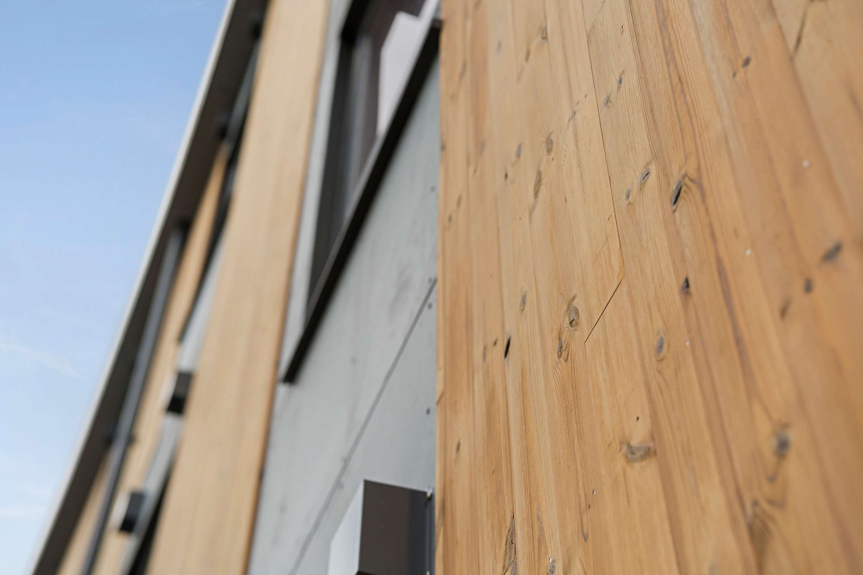 Primer plano de una pared de madera con veta y nudos bien visibles, que sugiere un material natural.