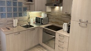 A modern kitchen with a built-in oven, a microwave, a sink, and a coffee maker. - Schöne Ferienwohnung App.36 mit Privatstrand (Gambarogno)