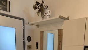 A bathroom with a white vanity, a mirror, and a shelf with decorative items. - Schöne Ferienwohnung App.36 mit Privatstrand (Gambarogno)