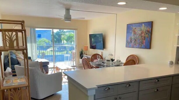 A modern kitchen with a large island, dining area with chairs, and a view of the outdoors.